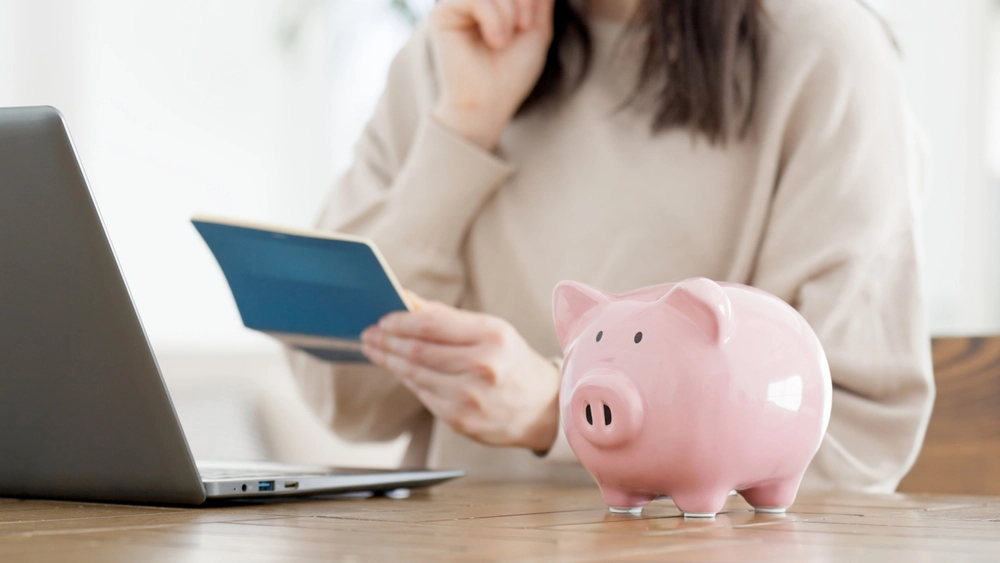 Line of Credit vs. Installment Loan Finances A woman checking her finances next to a piggy bank
